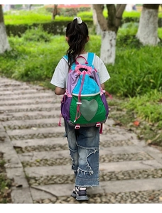 Detail of colorful patchwork backpack with heart mesh pocket on a child in a park
