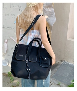 Detail of black canvas tote bag with multiple pockets and shoulder strap being worn