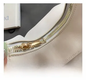 Detail of premium gold-tone zipper and embossed logo on off-white ruffled cloud bag