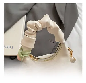 Close-up of pleated handle bag with a silk scarf and gold metal hardware detail