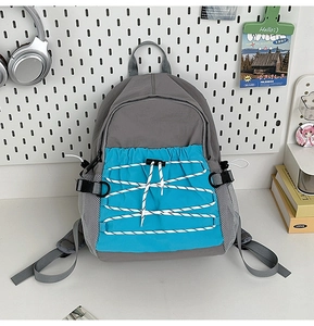 Detail van grijs-blauwe schoolrugzak met elastische gekruiste bungeekoorden aan voorkant