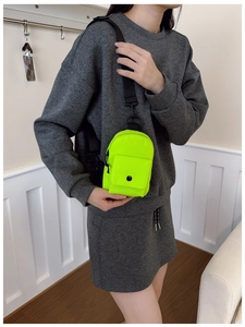Detailed view of neon green mini crossbody bag with adjustable strap worn by model