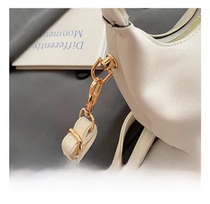 Close-up of premium gold-toned metal hook hardware on white lychee grain leather bag