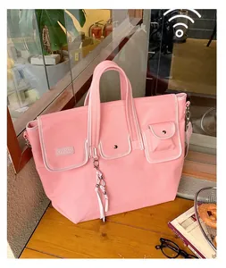 Pink canvas tote bag with QIYUAN logo and tassel detail on a wooden cafe table