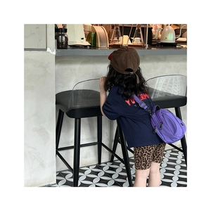Detail of children's purple canvas crossbody bag with adjustable strap worn by a child