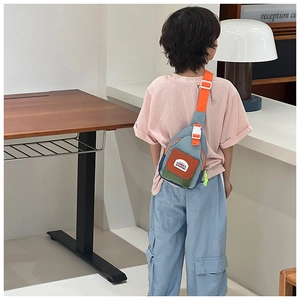 Close-up of kids color-block canvas chest bag with adjustable orange strap and mountain label