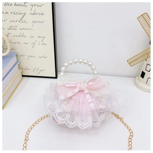 Détail du sac en dentelle rose avec grand nœud en soie et poignée en perles pour filles