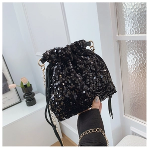 Detailed macro shot of black sequin bucket bag with drawstring and gold chain strap