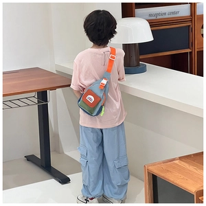 Detail of multi-color kids sling bag with adjustable orange strap and mountain patch