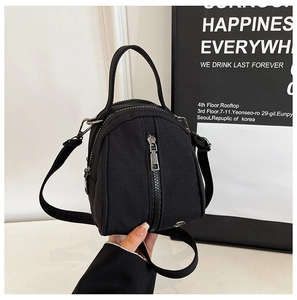 Detail view of the black nylon mini shell bag with dual zipper compartments and round logo