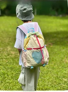 Outdoor view of child wearing colorful pastel drawstring backpack with blue heart mesh pocket
