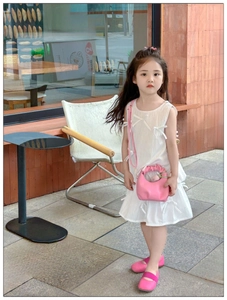 Close-up of a stylish white sleeveless dress with 3D bows and a pink pleated crossbody bag