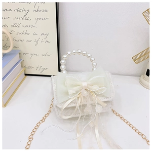 Détail du sac à main enfant avec nœud en dentelle, perles et bandoulière chaîne dorée