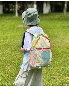 Outdoor shot of child wearing a multi-color heart mesh backpack with drawstring closure