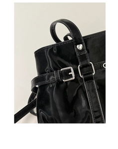 Close-up of black glossy tote bag with silver heart rivet and buckle detail