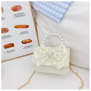 Détail d'un sac pour fille en dentelle blanche avec anse en perles et décor de couronne