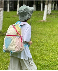 Outdoor shot of a colorful patchwork drawstring kids backpack with heart mesh detail