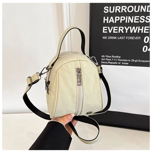 Close-up of cream mini shell crossbody bag with vertical zippers and black straps