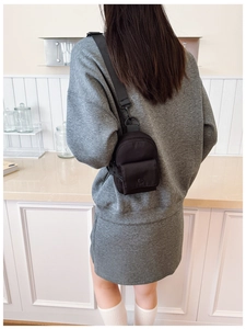 Rear view of a child wearing a black mini nylon chest bag with adjustable strap