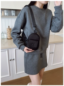 Mini black nylon crossbody chest bag shown on a model wearing grey sportswear