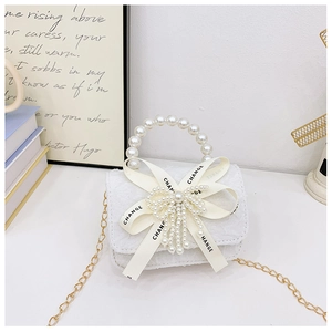 Détail du sac fille en dentelle blanche avec gros nœud, poignée perle et chaîne dorée