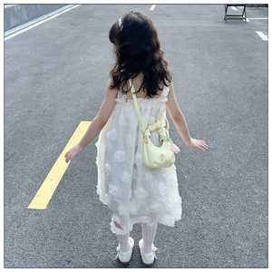 Detail of a white floral dress for girls paired with a yellow pleated cloud shoulder bag