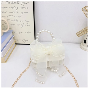 Détail du sac blanc avec nœud en organza, poignée en perles et franges de perles chic