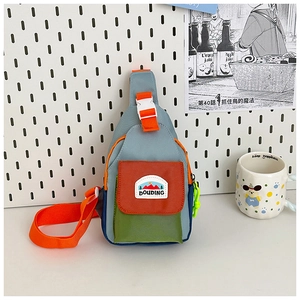 Detail of multi-color nylon kids chest bag featuring mountain patch and orange strap