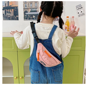 Pink canvas kids chest bag with orange zippers worn by a child in a casual outdoor setting