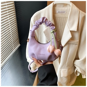 Close-up of purple pleated kids crossbody bag with floral charm and branded logo