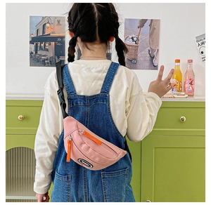 Detail of pink canvas kids chest bag with orange zippers and adjustable strap shown on model