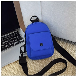 Close-up of electric blue nylon kids crossbody bag on a textured carpet with a laptop