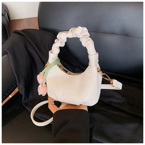 Detailed macro view of white pleated crescent bag with gold zipper and pink flower charm