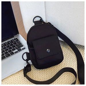Close-up of black nylon crossbody bag with zipper, metal snap pocket, and wide fabric strap