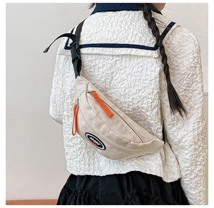 Detail of off-white kids canvas chest bag with sport logo and bright orange zipper pull