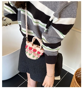 Close-up of pink crochet shoulder bag with red tulip patterns and pearl bead button detail