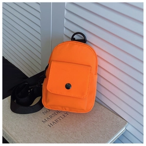 Detail of orange nylon kids chest bag featuring front utility pocket and black buckle