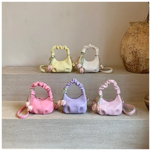Detail of colorful ruched cloud bags with tulip charms and shoulder straps on stone steps