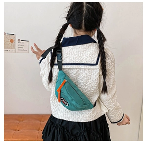 Rear view of a child wearing a teal green nylon chest bag with sport logo and orange zipper