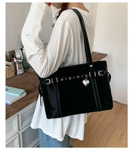 Detail of black faux leather tote with silver rivets and a heart-shaped metal charm