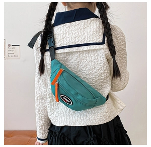 Detail of teal kids sport chest bag with orange double zippers and adjustable strap