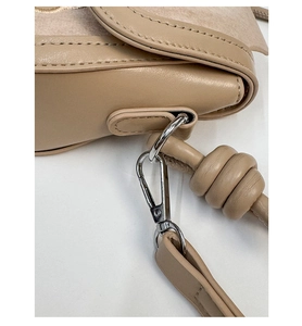 Macro di pelle beige con gancio in metallo argento e dettaglio della tracolla con nodo unico