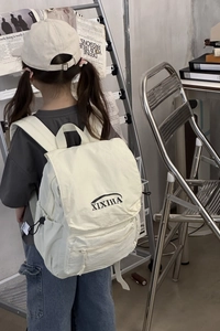 Detail of a beige kid backpack with XIXIHA logo and adjustable side drawstring