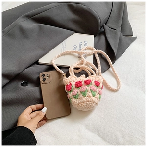 Detail of crochet mini bag with tulip floral pattern next to a smartphone for size scale