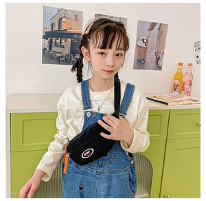 Detailed view of child wearing black sports crossbody bag with orange zippers