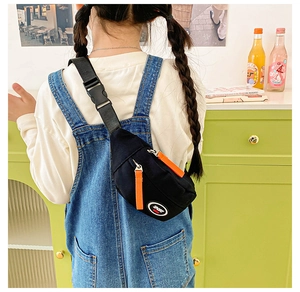 Close-up of kids black sport chest bag with orange zipper detail and adjustable strap