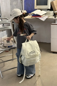 Close-up of cream canvas kids backpack with front pocket and adjustable straps