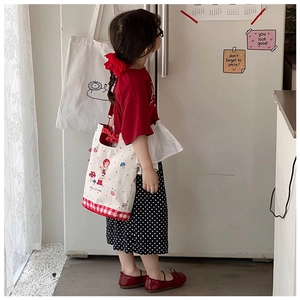 Detail of kids canvas shoulder bag featuring red plaid pattern and cute cartoon prints
