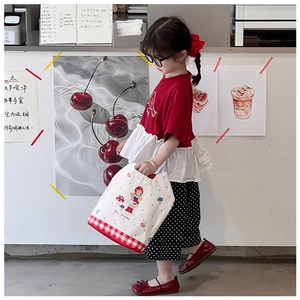 Close-up of children's white canvas bag with red plaid trim and cute mushroom prints