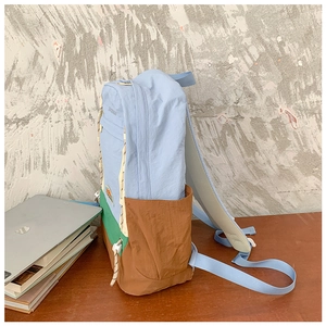 Détail du sac à dos enfant bicolore avec logo montagne sur tissu bleu, vert et marron